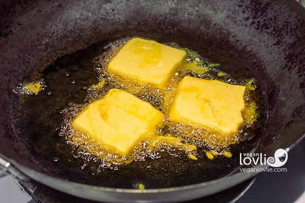 shallow frying battered tofu in a wok